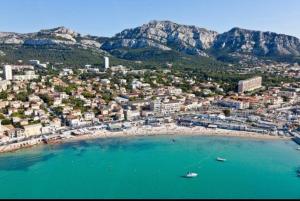 eine Luftansicht auf einen Strand mit Gebäuden und Bergen in der Unterkunft Appartement la plage de la pointe rouge in Marseille