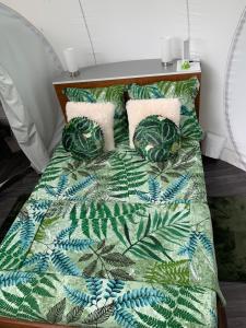 a bed with a green and white blanket and pillows at CHALET & MAISONS BULLES Deluxe in Bouillante