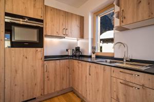 a kitchen with wooden cabinets and a sink and a window at Apt Fichte - Nockerhof in Andrian