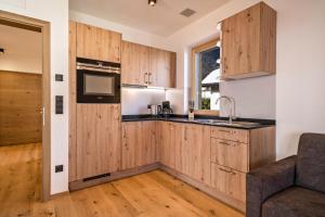 een keuken met houten kasten en een bank in een kamer bij Apt Fichte - Nockerhof in Andrian