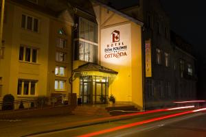 a building with a sign on the side of it at night at Hotel Dom Polonii in Ostróda