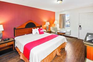 um quarto com uma cama grande e uma parede vermelha em OYO Hotel Blytheville AR I-55 em Blytheville