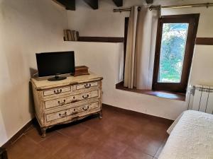 a bedroom with a television on a dresser with a window at Cal Miquel de Ventolà in Ventolà