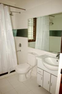 a white bathroom with a toilet and a sink at East End Retreat in New Delhi