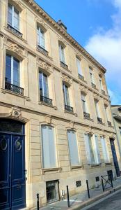 a large building with a blue door on a street at Maison Manège Bordeaux Centre in Bordeaux