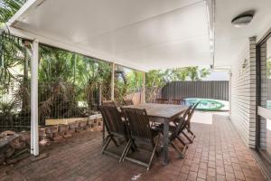 an outdoor patio with a wooden table and chairs at Lakeshores 41 Coongarra in Kawana Waters
