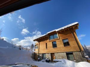 domek z bali w śniegu z niebieskim niebem w obiekcie Chalety Jasná Apartmány Bor w Demianowskiej Dolinie