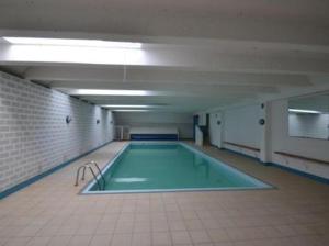 a large swimming pool in a room with a tile floor at Klif studio 612 La Panne in De Panne