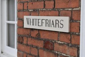 una señal en una pared de ladrillo con la palabra terrores blancos en Whitefriars, en Rye