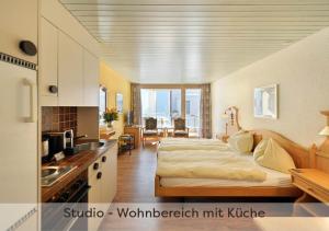 a bedroom with a bed and a kitchen with a sink at Aparthotel Eiger *** - Grindelwald in Grindelwald