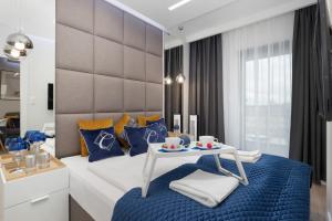 sypialnia z łóżkiem z niebieskimi poduszkami i stołem w obiekcie Apartamenty Gardenia Seaside by Noclegi Renters w Dziwnowie