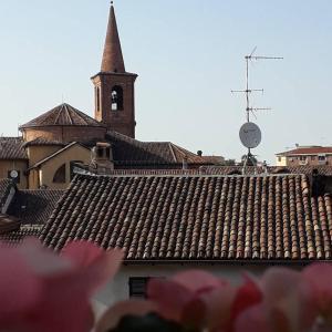 eine Kirche mit einem Uhrturm und einem Dach mit rosa Blumen in der Unterkunft La Casa sui Tetti in Novi Ligure