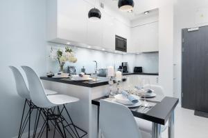 kuchnia z białymi szafkami, stołem i krzesłami w obiekcie Apartamenty Gardenia Seaside by Noclegi Renters w Dziwnowie