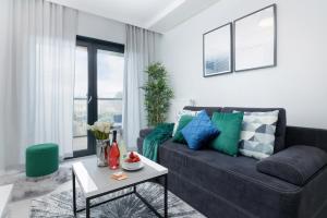 a living room with a black couch and a table at Apartamenty Gardenia Seaside by Renters in Dziwnów