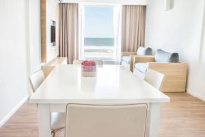 a white dining room with a white table and chairs at Pinamar Beach Resort in Pinamar