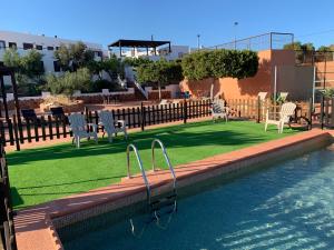 una piscina con sillas y un patio con césped en Hospederia Rural Los Palmitos, en El Pozo de los Frailes