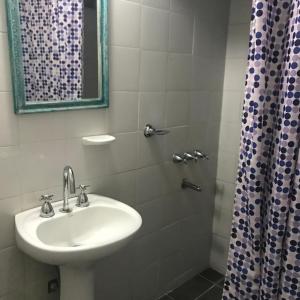 y baño con lavabo y ducha con espejo. en Hotel Are Pora en Gualeguaychú