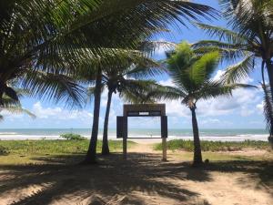 a sign on the beach between two palm trees at Morada do Sol in Valença