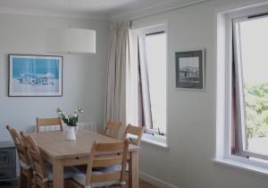 uma sala de jantar com uma mesa e cadeiras e duas janelas em Apartment Sula Bassana em North Berwick
