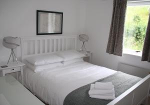 a bedroom with a bed with white sheets and a window at Apartment Sula Bassana in North Berwick
