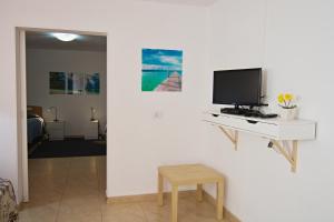 sala de estar con TV en una pared blanca en La Casita, a dos pasos de la playa, en Los Cristianos