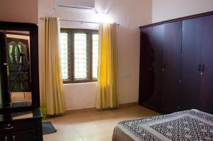 1 dormitorio con cortinas amarillas, 1 cama y espejo en Muralee's Riverside Villa in Kochi, en Kochi