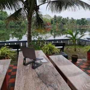 un ordenador portátil sentado en un banco junto a un lago en Muralee's Riverside Villa in Kochi, en Kochi
