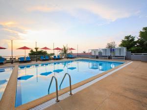 a large swimming pool with chairs and umbrellas at Huahin Bluewave residence by kzy in Hua Hin