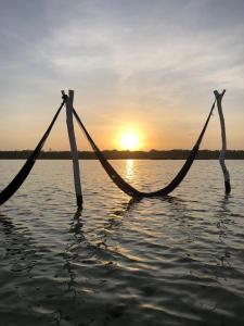 dos hamacas en el agua con la puesta de sol en el fondo en Pousada Chez Loran lagoa do paraiso en Jijoca de Jericoacoara