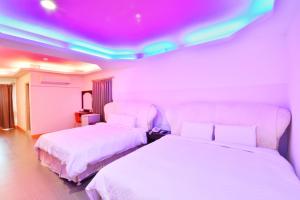 two beds in a room with pink and purple lights at Kenting Coral Sea Resort Hotel in Kenting