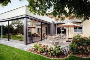 une extension d'une maison avec des portes coulissantes en verre et une terrasse dans l'établissement Landpension Kohler, à Brackenheim