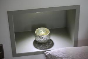uma taça de vidro sentada numa prateleira ao lado de uma cama em Pudswell Studio em Burford