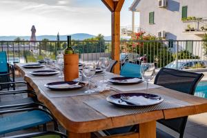 een houten tafel met glazen en een fles wijn bij Villa Dada i Dida in Milna