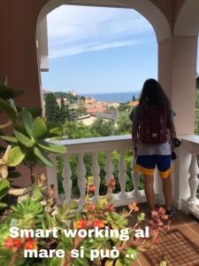 a girl standing on a balcony looking out at the ocean at Residence Hotel Edy in Imperia