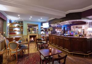 a bar in a restaurant with tables and a fireplace at The Ormond At Tetbury in Tetbury