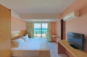 um quarto de hotel com uma cama e uma televisão e o oceano em Vip Praia Hotel em Natal