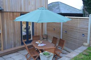 a table and chairs under an umbrella on a patio at Cedar Lodge 2 ensuite bedroom cottage near Bath in Box