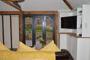 a living room with a yellow couch and a television at Cedar Lodge 2 ensuite bedroom cottage near Bath in Box