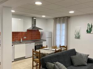 a kitchen and living room with a table and a couch at Os Arcos - Apartamentos Turísticos in Portomarin
