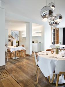 uma sala de jantar com mesas brancas e cadeiras brancas em Notarishuys "Pure Hotel" em Diksmuide