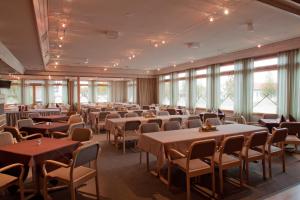 una sala da pranzo con tavoli, sedie e finestre di Hotelli Jussan Tupa a Enontekiö