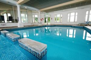 a large swimming pool with blue water in a building at Abbey Lawn Hotel in Torquay