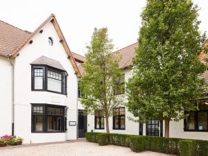 a white house with black windows and trees at Notarishuys "Pure Hotel" in Diksmuide