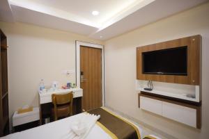a hotel room with a bed and a flat screen tv at The Avenue Hotel Ballygunge in Kolkata