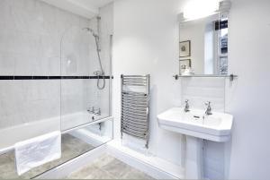 a white bathroom with a sink and a shower at The Ormond At Tetbury in Tetbury