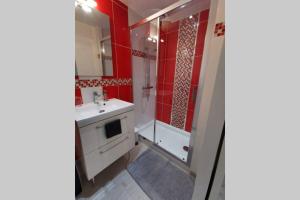 a bathroom with red walls and a sink and a shower at Appartement F2 COSY proche de l'HYPER CENTRE in Caen