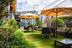 un patio con 2 sombrillas, mesas y sillas en Hotel Rennova en La Paz