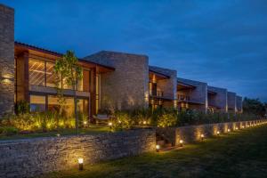a house with a stone wall and lights at Hotel Aretê in Búzios