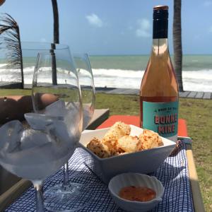 - une bouteille de vin, un verre et de la nourriture sur une table dans l'établissement Pousada Yemanjá Toré, à Barra de Camaratuba