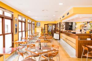 a restaurant with tables and chairs and yellow walls at Sagitario Hostal Ciutadella in Ciutadella